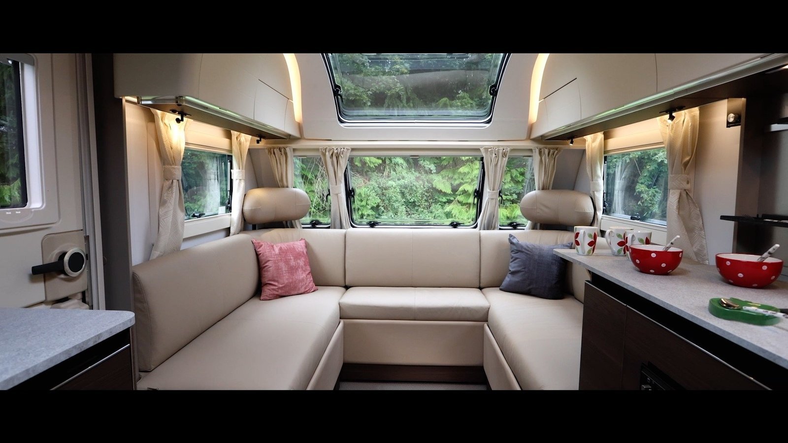 A bright modern 2026 touring caravan interior with a practical lounge and fixed bed