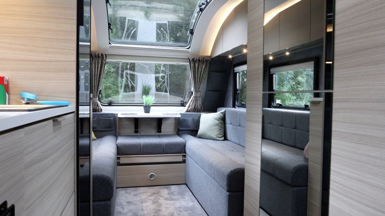 A bright modern caravan interior showing a practical lounge and kitchen layout
