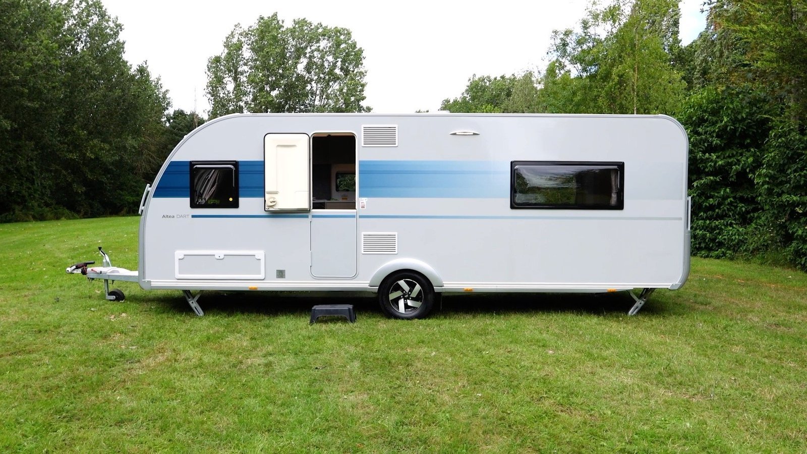 A modern touring caravan set up at an attractive countryside campsite